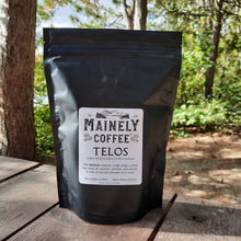 A black bag of coffee with a label saying, "Telos - Organic and Rainforest Alliance Certified"